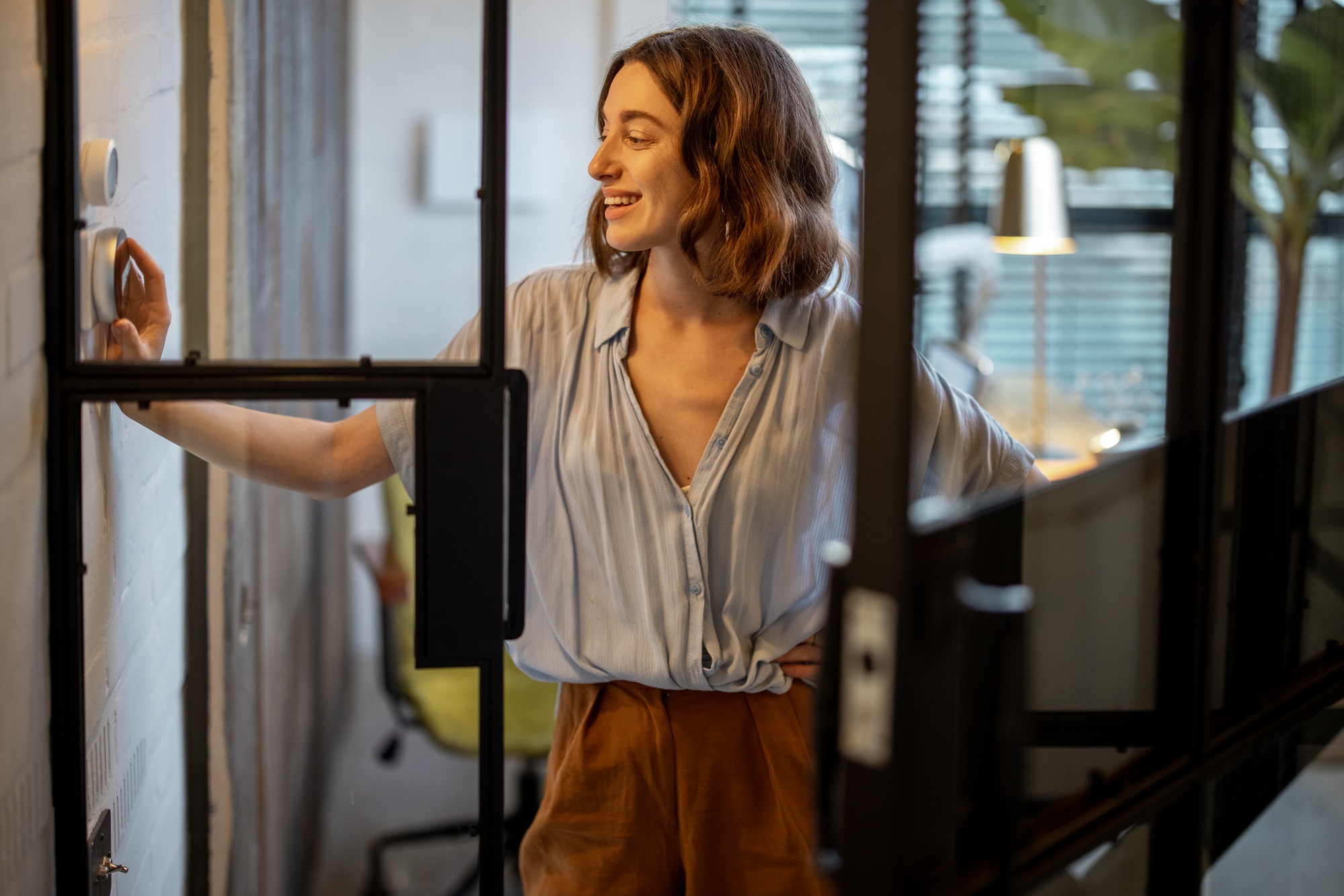 Woman controlling temperature with a thermostat at home
